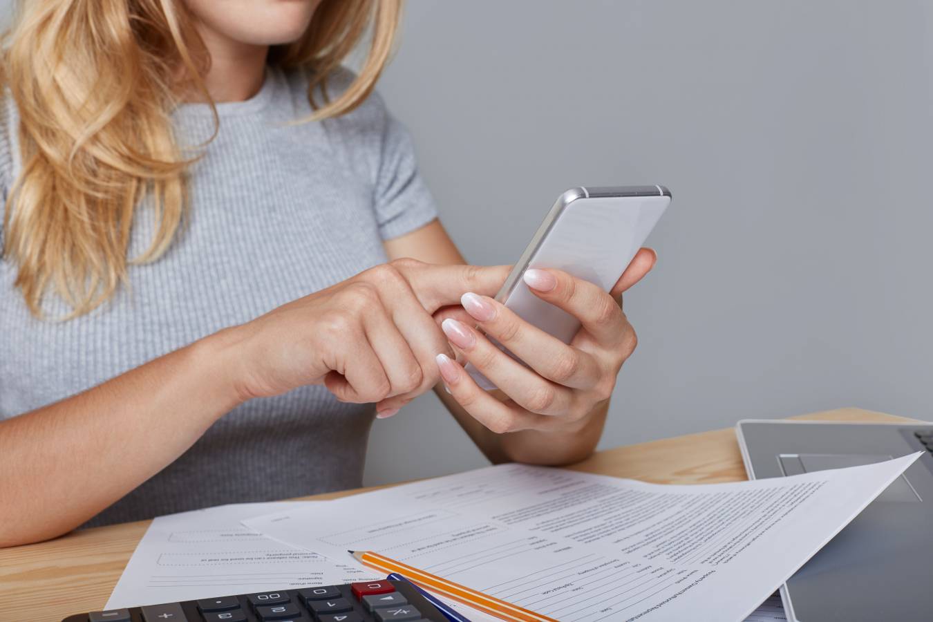 unrecognizable-woman-holds-modern-mobile-phone-hands-sits-work-table-surrounded-with-documents-laptop-pencil-calculator-downloads-necessary-information-from-internet-job-technology (1).jpg